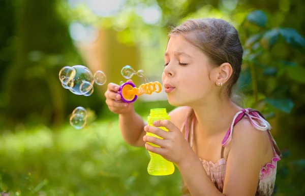 Niña está soplando una burbuja de jabón — Foto de Stock