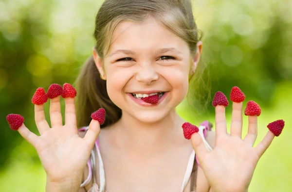 Young girl is holding raspberries on her fingers — Stock Photo, Image