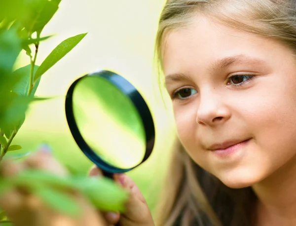 La fille regarde les feuilles d'arbre à travers la loupe — Photo