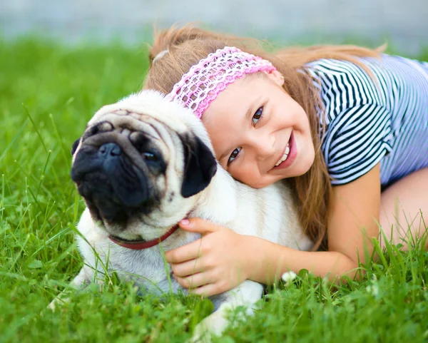 Little girl and her pug dog on green grass — Stock Photo, Image