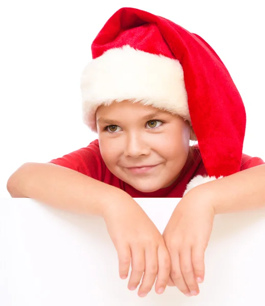 산타 모자에 있는 어린 소녀는 빈 보드를 들으십시오 — 스톡 사진