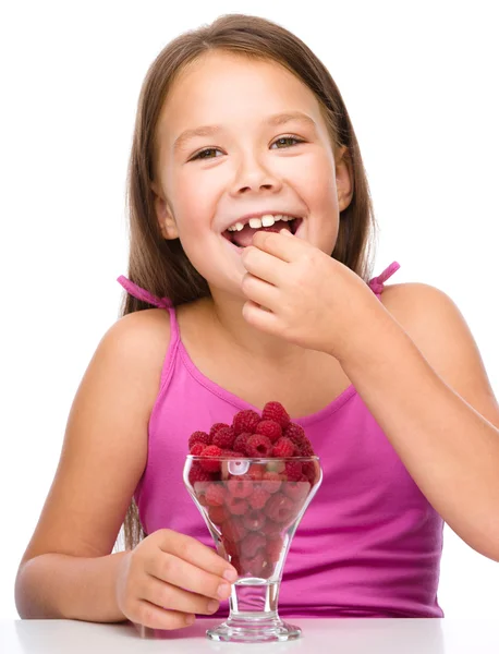 Happy little girl is eating raspberries — Stock Photo, Image