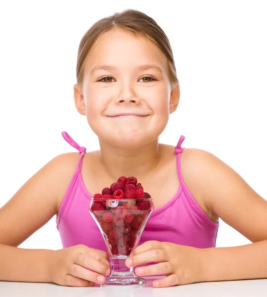 Happy little girl is eating raspberries — Stock Photo, Image
