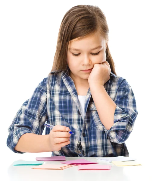 Meisje is het schrijven op kleur stickers met pen — Stockfoto