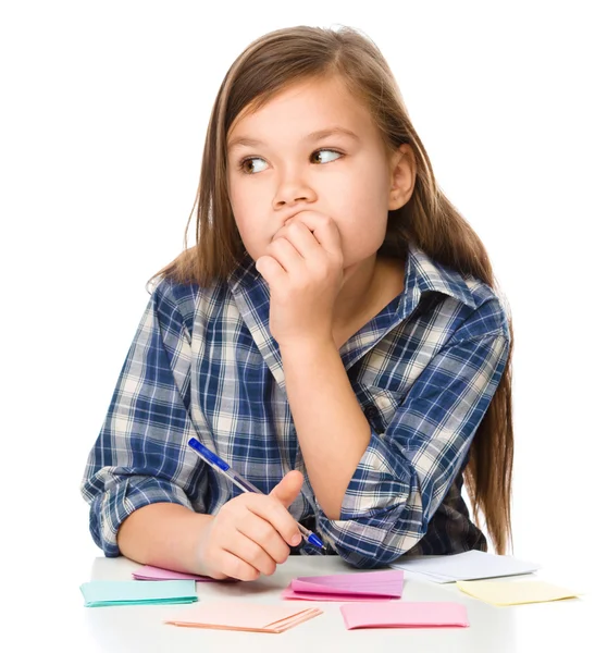 Chica está escribiendo en pegatinas de color usando pluma —  Fotos de Stock