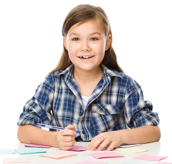 Menina está escrevendo em adesivos de cor usando caneta — Fotografia de Stock