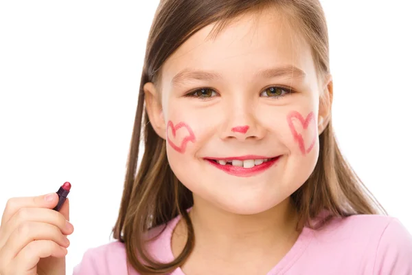 Little girl is applying lipstick on her cheek — Stock Photo, Image