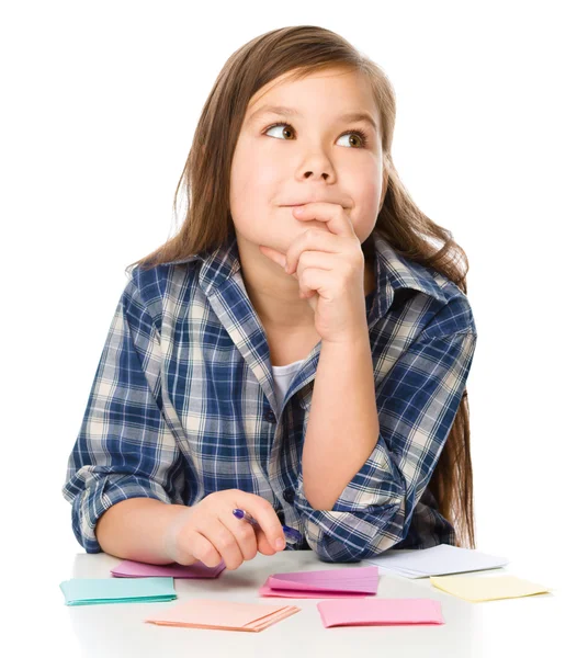 Chica está escribiendo en pegatinas de color usando pluma — Foto de Stock