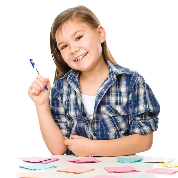 Chica está escribiendo en pegatinas de color usando pluma — Foto de Stock