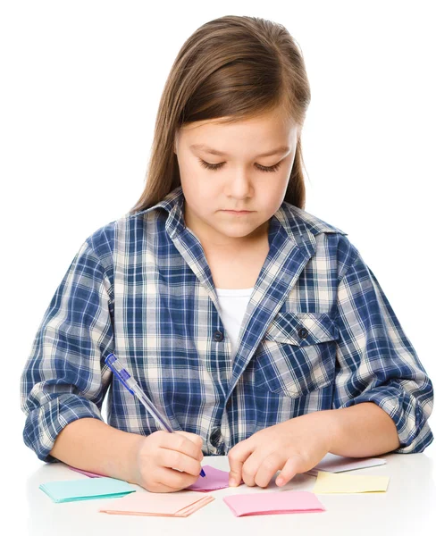 Girl is writing on color stickers using pen — Stock Photo, Image