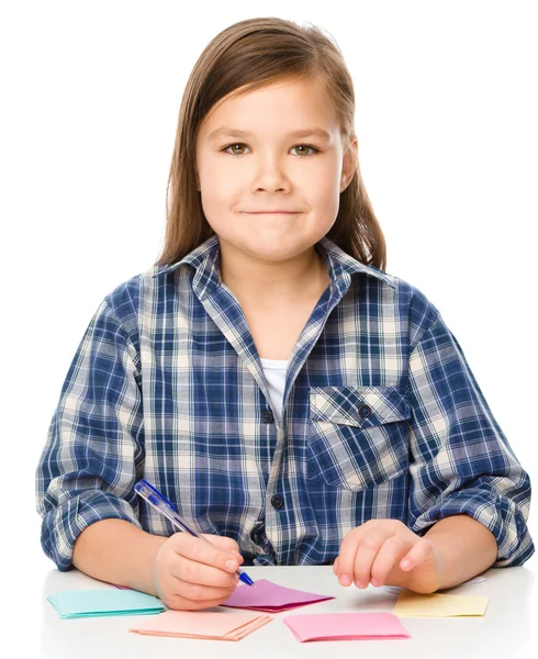 Дівчина пише на кольорових наклейках, використовуючи ручку — стокове фото