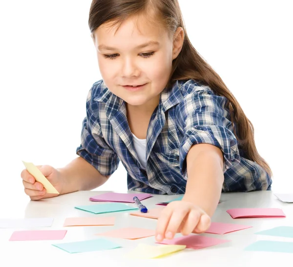 Ragazza sta scrivendo su adesivi a colori utilizzando penna — Foto Stock