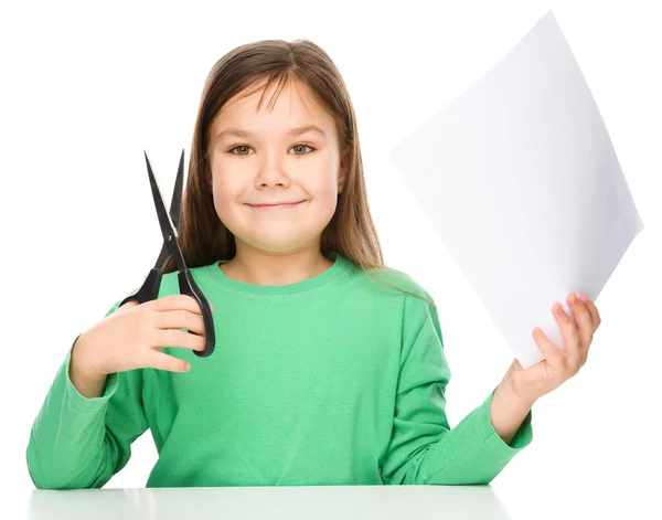 Menina está cortando papel usando tesoura — Fotografia de Stock