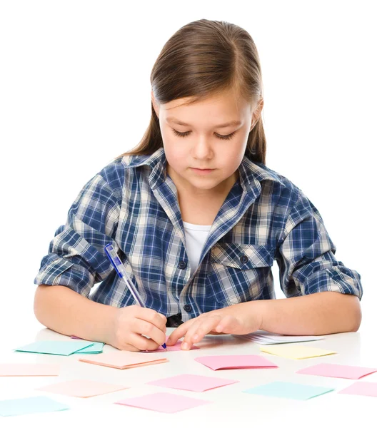 Chica está escribiendo en pegatinas de color usando pluma —  Fotos de Stock