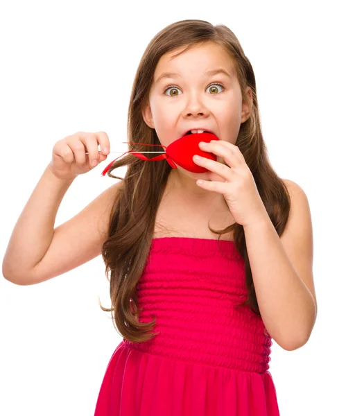 Portrait of a little girl biting red heart — Stock Photo, Image