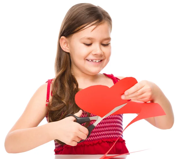 Retrato de una niña cortando el corazón rojo — Foto de Stock