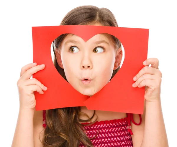 Little girl is looking through heart template — Stock Photo, Image