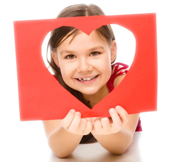 Little girl is looking through heart template — Stock Photo, Image