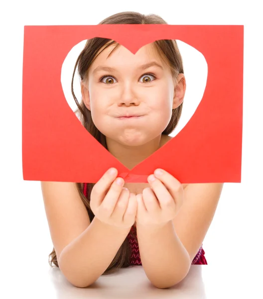 Little girl is looking through heart template — Stock Photo, Image