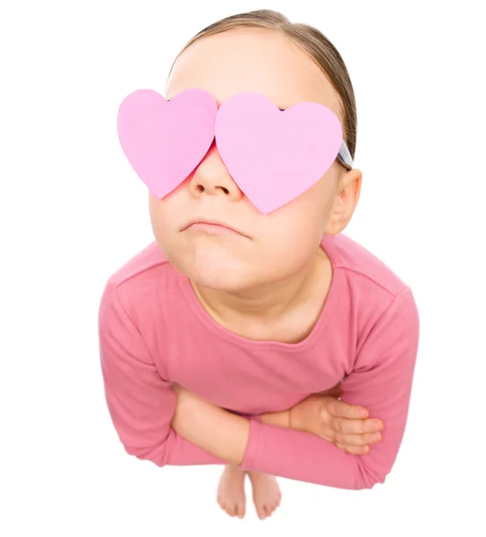 Маленькая девочка держит сердца над глазами — стоковое фото