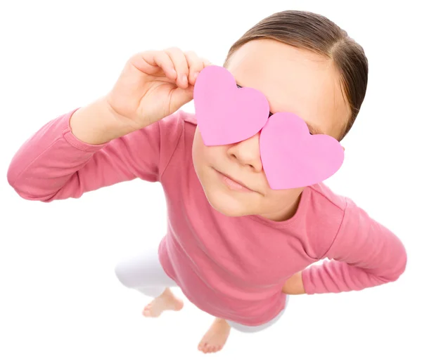 Menina está segurando corações sobre seus olhos — Fotografia de Stock