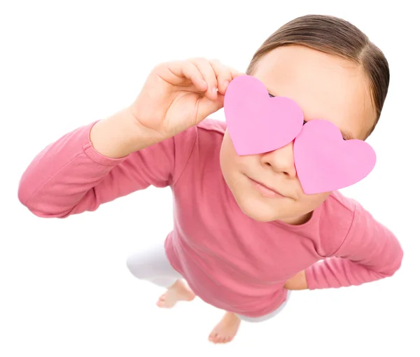 Little girl is holding hearts over her eyes — Stock Photo, Image