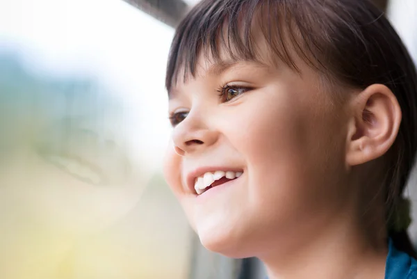 Glückliches Mädchen schaut durch Fenster — Stockfoto