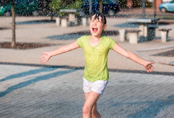 女の子は噴水を通じて実行されます。 — ストック写真