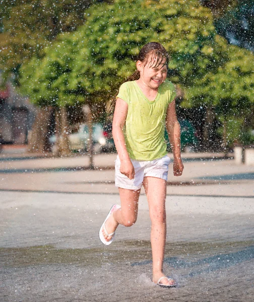 Mädchen läuft durch Springbrunnen — Stockfoto