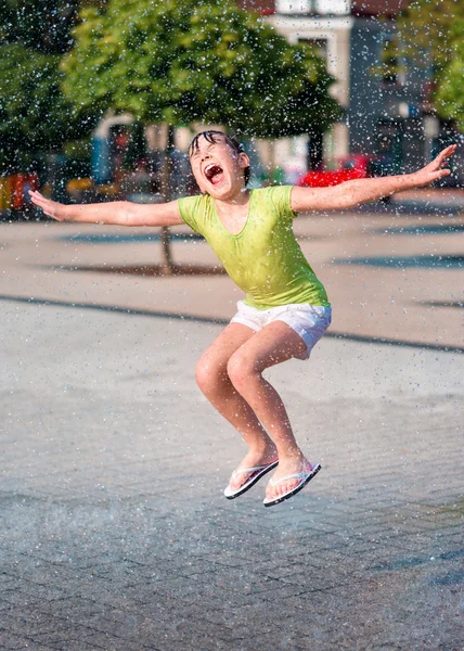 女の子は噴水を通じて実行されます。 — ストック写真