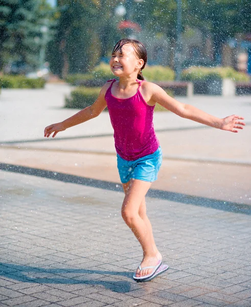 女の子は噴水を通じて実行されます。 — ストック写真