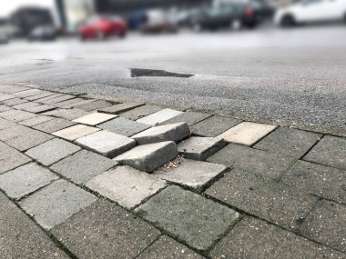 Yayalar için kaldırım taşları bakım eksikliği nedeniyle düzensizdir ve yayalar ve trafik için tehlikeye yol açabilir