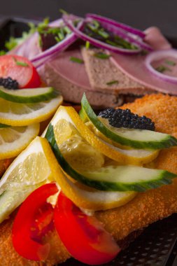 Smorrebrod a traditional Danish open sandwich that consists of a piece of dark rye bread, topped with cold cuts, pieces of meat or fish, cheese or spreads, and garnishes. Close up image.