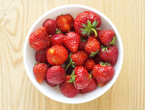 Rote Erdbeeren im Teller isoliert auf Holztisch — Stockfoto