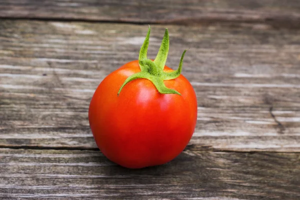 Een verse, rijpe tomaat op een houten bord. — Stockfoto