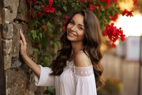 Gelukkig lachend meisje tegen bloemen — Stockfoto