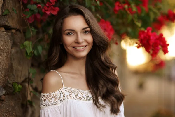 Menina sorridente feliz contra flores — Fotografia de Stock