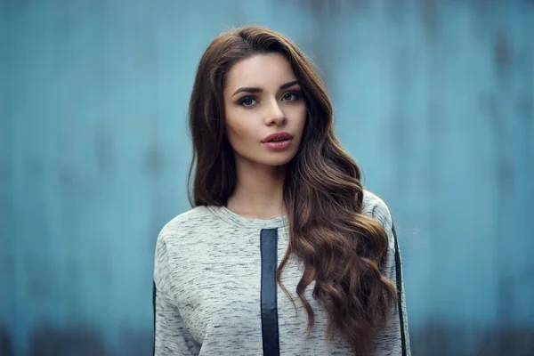 Mooi meisje in hoodie tegen blauwe muur — Stockfoto