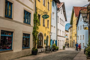 Fuessen, Almanya 26 Mayıs 2019 - Dağlar arasında yeşil yağmurlu vadide kaynamış kiremit çatılı sıcacık alp evleri. Küçük Alman kasabası Fussen.