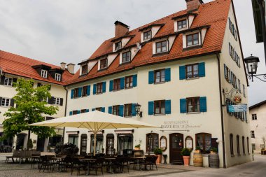 Fuessen, Almanya 26 Mayıs 2019 - Dağlar arasında yeşil yağmurlu vadide kaynamış kiremit çatılı sıcacık alp evleri. Küçük Alman kasabası Fussen.