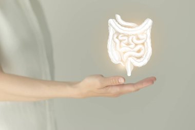 Beyaz elbiseli tanınmayan bir kadın hasta, ellerinde işaretlenmiş bağırsak var. İnsan sindirim sistemi kavramı.