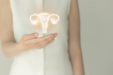 Beyaz elbiseli tanınmayan bir kadın hasta, ellerinde çizilmiş rahmi var. İnsan üreme sistemi kavramı.