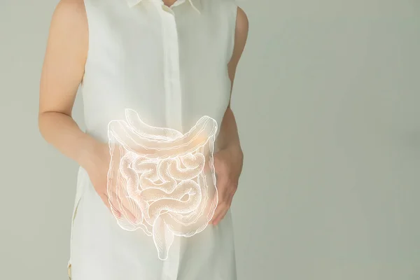 Unrecognizable female patient in white clothes, highlighted handrawn intestine in hands. Human digestive system issues concept.