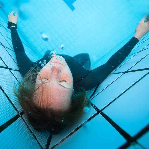 Buzo femenino con los ojos cerrados bajo el agua en la piscina —  Fotos de Stock