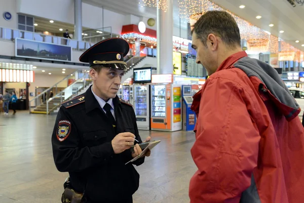 A police officer checks the citizen's information database at the entrance to the Moscow airport. — Stock Photo, Image