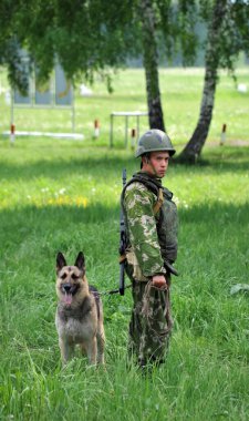 JURGA, SIBERIA, RUSSIA - 6 Haziran 2011: Patlayıcıları aramak için çoban köpeğiyle birlikte askeri köpek eğitmeni