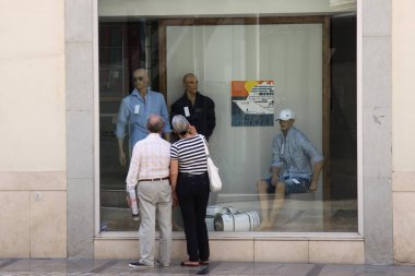 MALAGA, İSPAN-24 HAZİRAN 2011: Mağaza vitrininde yaşlı bir çift