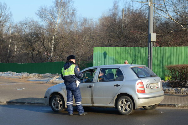 ОДИНЦОВО, МОСКОВСКАЯ ОБЛАСТЬ, РОССИЯ - 20 февраля 2016 года: Инспектор дорожно-патрульной службы полиции проверяет документы водителя остановленного автомобиля