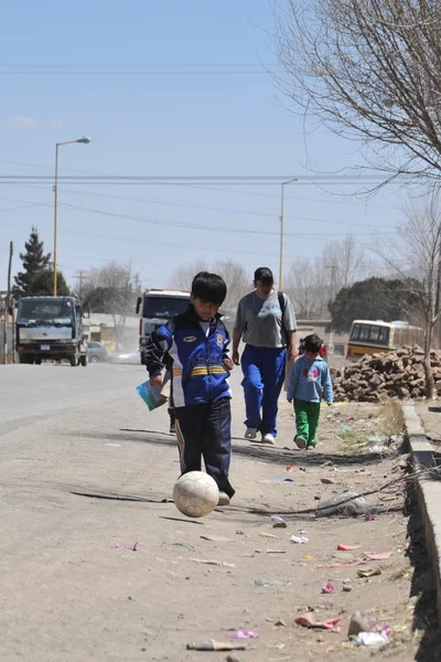 Unknown boy playing with a ball on the road of Oruro — стокове фото