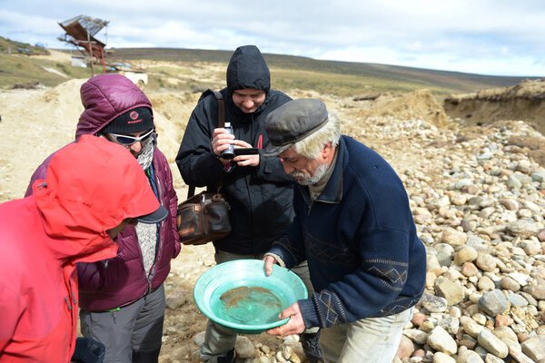 Gold digger shows tourists alluvial gold sand mined in the mine on the island of Tierra del Fuego.